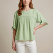 Green linen summer blouse for women by FJØRNA, flowy and lightweight, shown on a model with short sleeves and a relaxed fit.
