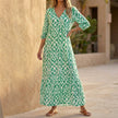 Green V-neck maxi dress with ruffled hem by FJØRNA, flowing fabric, and elegant silhouette perfect for summer wear.