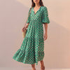 Green FJØRNA midi dress with flowing V-neck, puff sleeves, and tiered skirt, perfect for elegant daytime or evening wear.