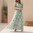 Green FJØRNA A-line maxi dress with V-neck and flutter sleeves, flowing fabric and elegant design for casual or formal wear.