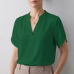 Green FJØRNA women's summer blouse with V-neck, short sleeves, and flowy fabric, perfect for warm weather.