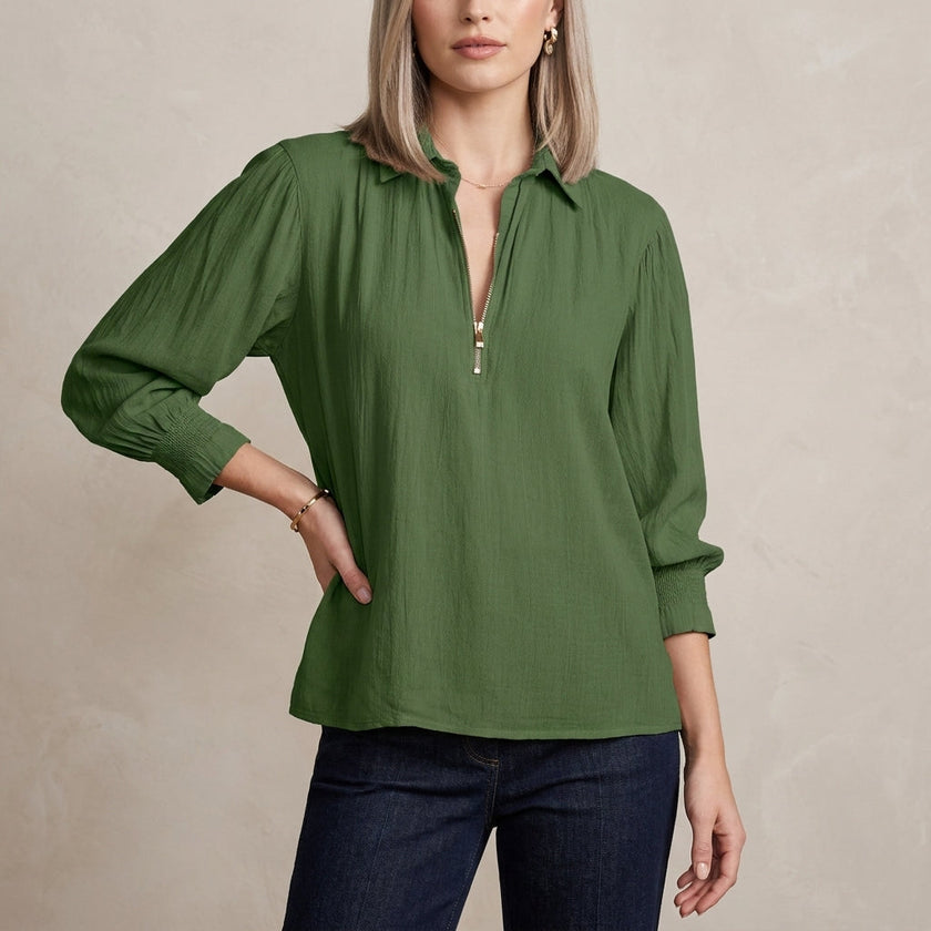 Green FJØRNA summer blouse for women with long sleeves and smocked design, shown on a model.
