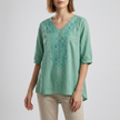 Green FJØRNA women's summer blouse with floral pattern, V-neck, linen fabric, and slit detail, perfect for warm weather.