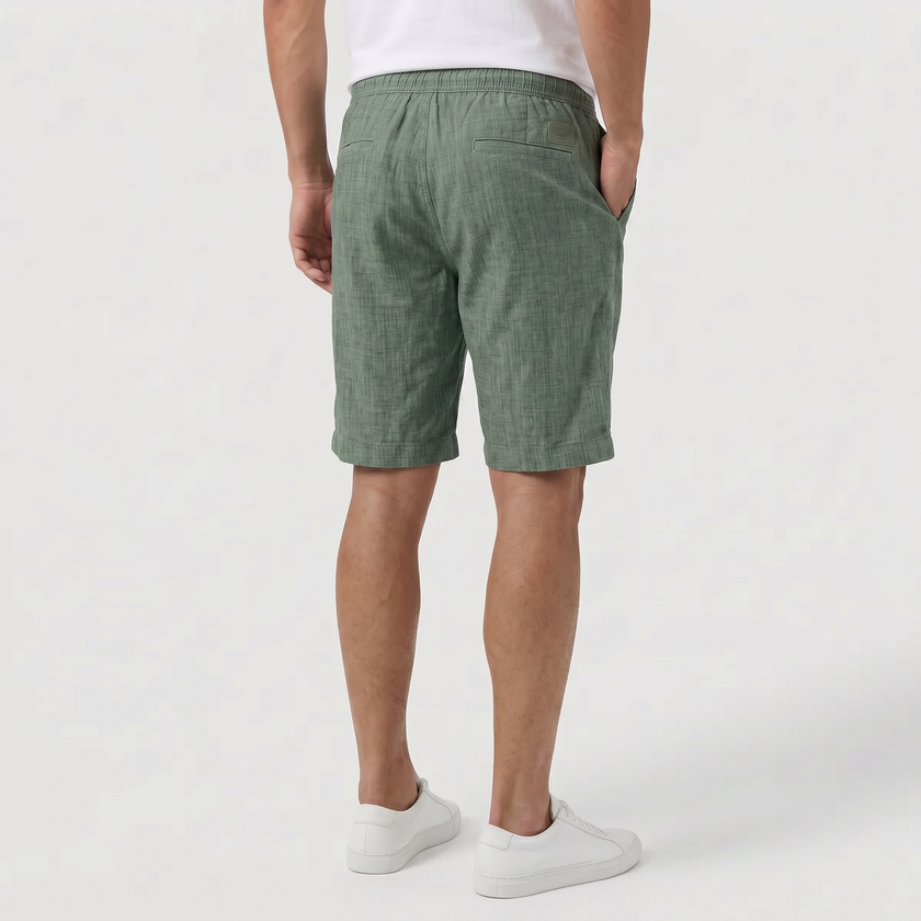 FJØRNA men's green linen shorts with elastic waistband and drawstring, shown from the back, perfect for summer beachwear.