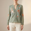 FJØRNA women's summer floral blouse with V-neck and long sleeves, in vibrant green fabric, perfect for warm weather style.