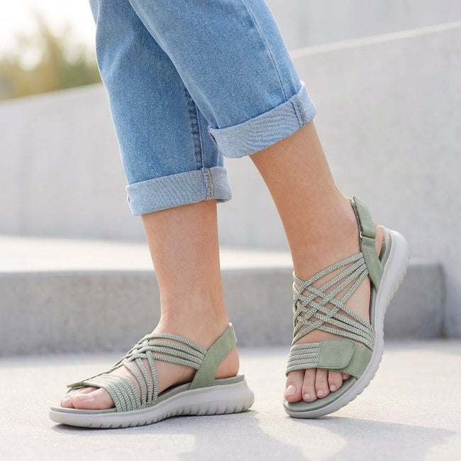 Green FJØRNA orthopedic criss-cross strappy women's sandals with adjustable straps on a model's feet.
