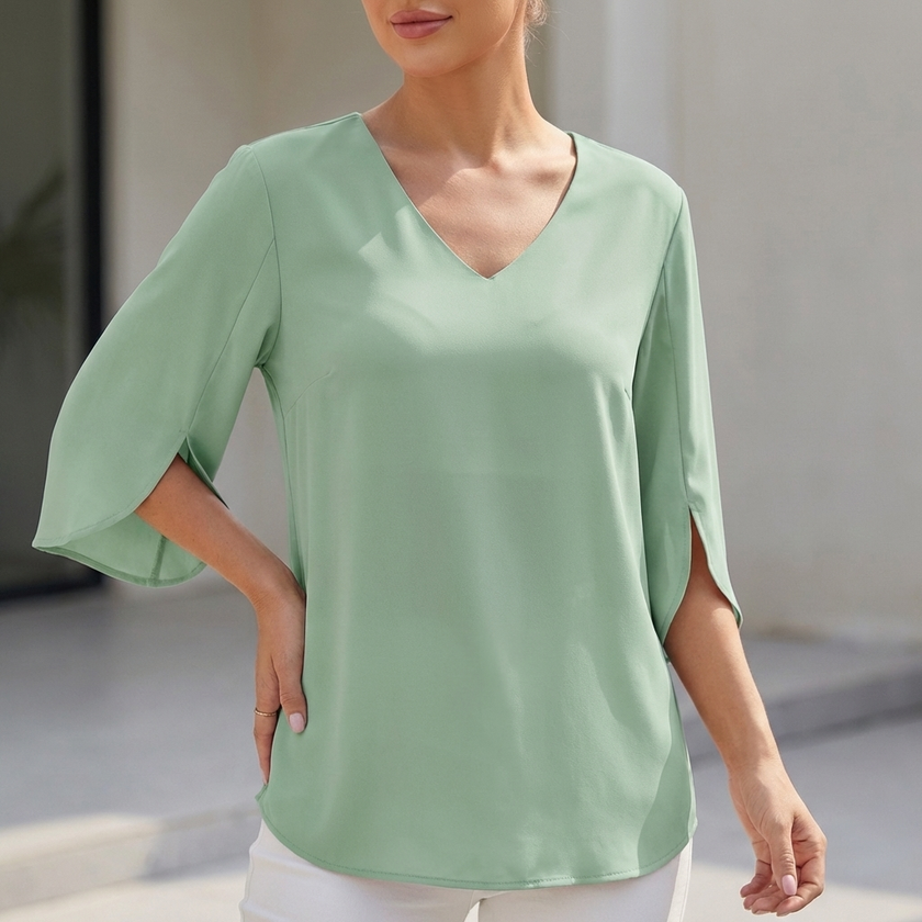 Green women's V-neck blouse with curved hem and slit sleeves by FJØRNA, showcasing a flowing, stylish top for casual or dressy wear.