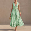 Green FJØRNA pleated A-line maxi dress with V-neck and balloon sleeves, flowing and elegant on a model.