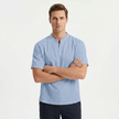 Men's light blue linen short sleeve Henley T-shirt by FJØRNA, shown with crossed arms, casual and breathable summer top.