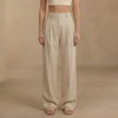 FJØRNA high-waist pleated wide-leg women's trousers displayed on a hanger, showcasing their flowy fabric and tailored fit.