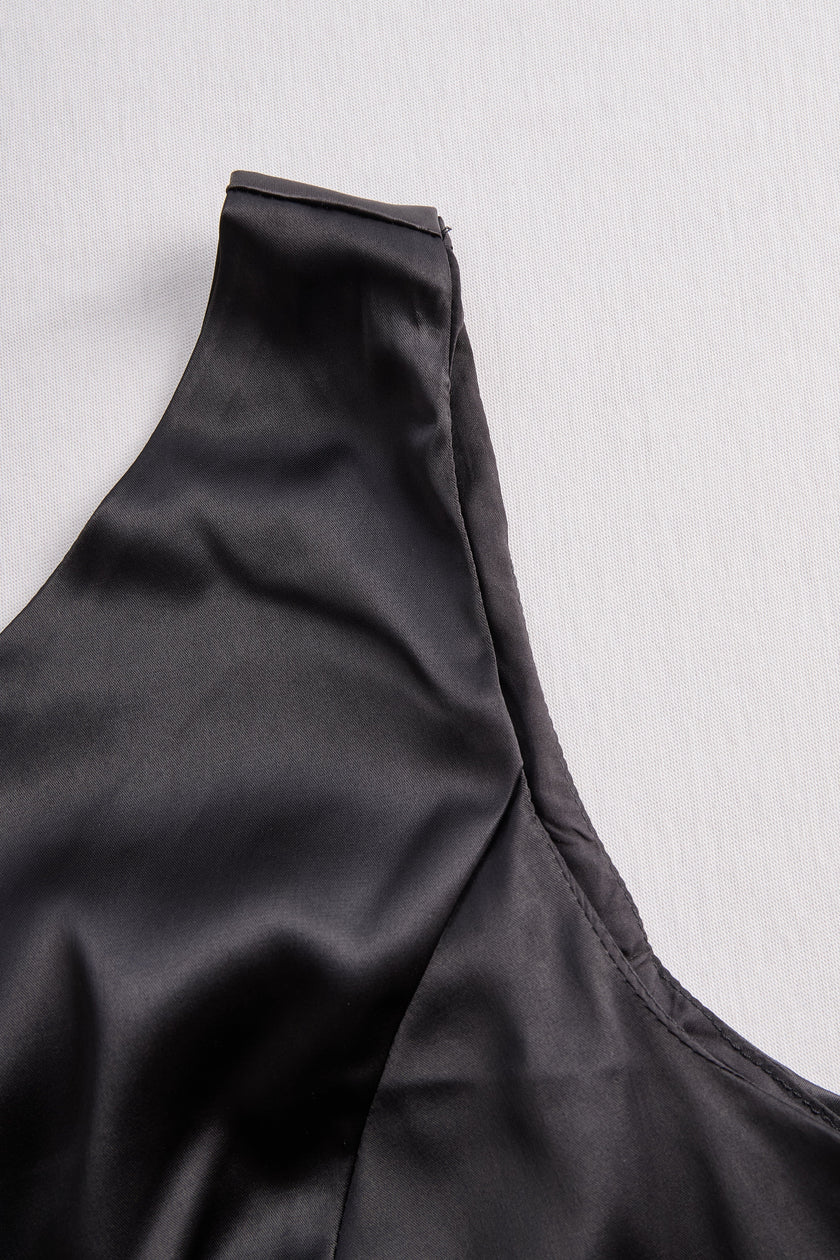 FJØRNA Glamorous Allure black one-shoulder maxi dress displayed on a hanger, showcasing elegant design and flowing fabric.