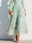 FJØRNA floral print long-sleeved V-neck pleated dress displayed on a hanger with a soft fabric texture and elegant floral pattern.