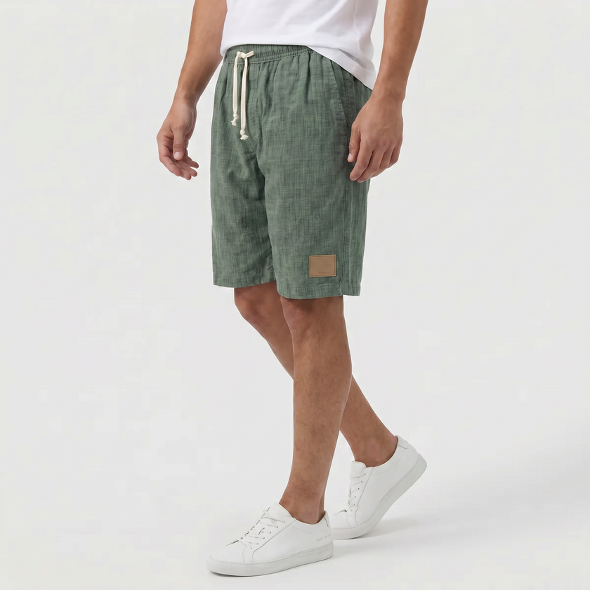 Men's khaki linen shorts with elastic waistband and drawstring, shown from the side, suitable for summer beachwear by FJØRNA.