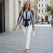FJØRNA women's summer blouse with striped pattern and puff sleeves, styled in a casual outdoor setting.