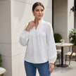 FJØRNA women's summer blouse featuring a V-neck, puff sleeves, and ruffle details, styled in a casual outdoor setting.