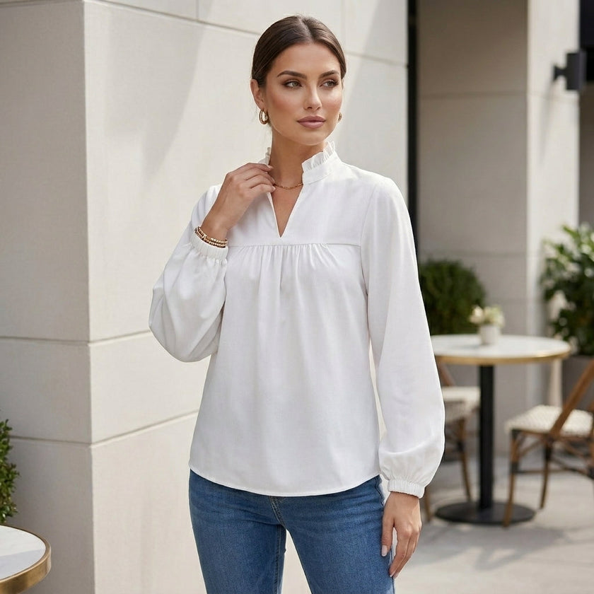 FJØRNA women's summer blouse featuring a V-neck, puff sleeves, and ruffle details, styled in a casual outdoor setting.