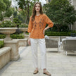 FJØRNA women's summer blouse with geometric pattern and button front, styled as a casual top in a lifestyle setting.