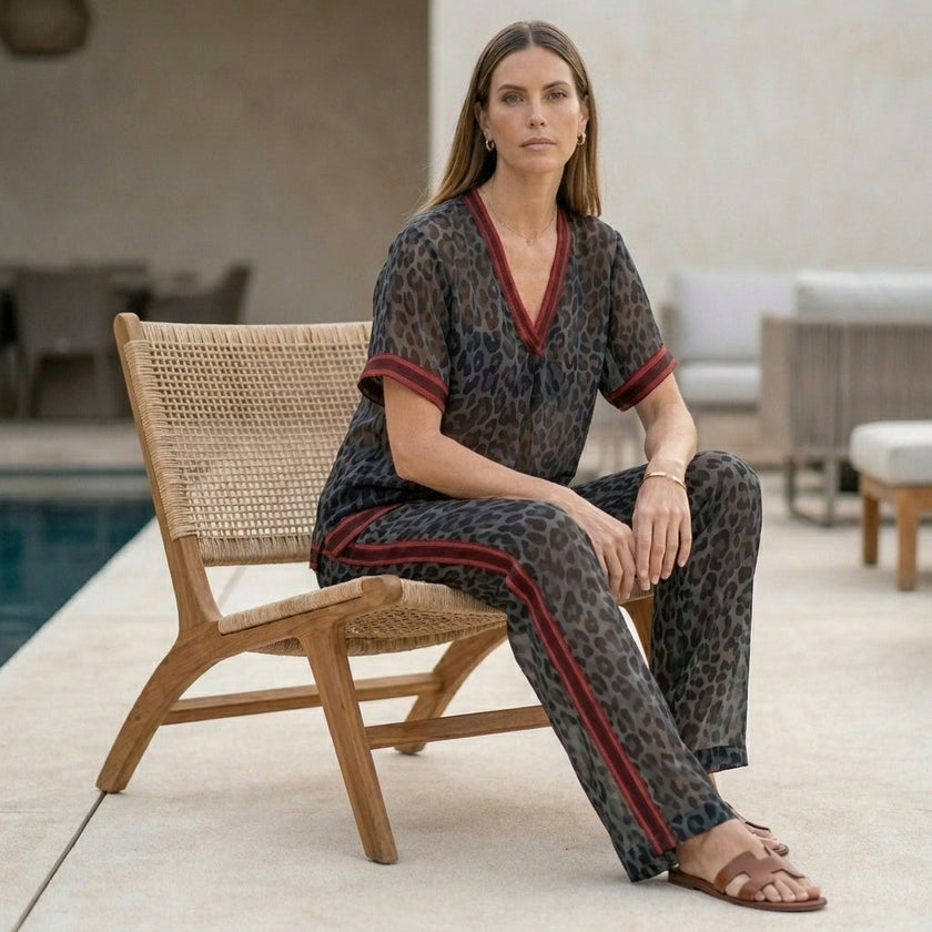 FJØRNA leopard print chiffon lounge set with relaxed fit, wide-leg pants and matching top, styled in a cozy indoor setting.