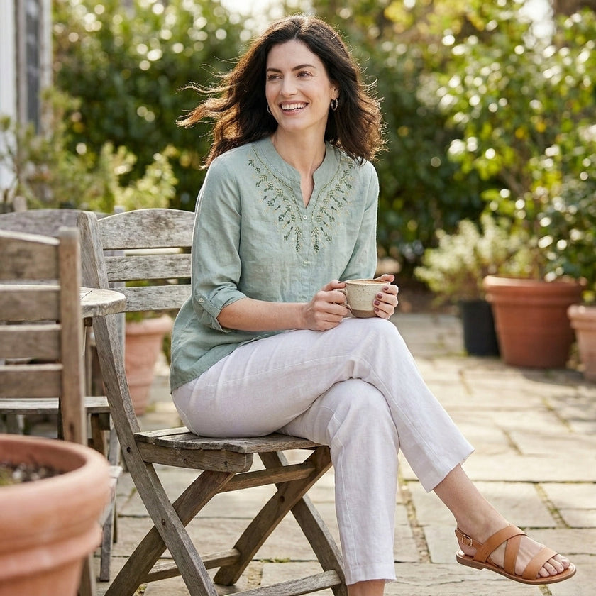 FJØRNA women's summer blouse in denim, flowy style, shown as a casual outfit in a lifestyle setting.