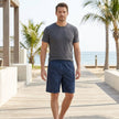Men's tropical leaf pattern loose-fit knee-length beach shorts with pockets by FJØRNA, shown in a relaxed lifestyle setting.