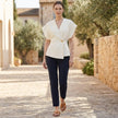 FJØRNA fitted wrap-front V-neck blouse with sculpted waist embellishment, styled as a women's top on a model in a casual setting.