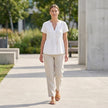 FJØRNA women's V-neck peplum blouse with pintuck details and curved hem, styled in a casual outfit.