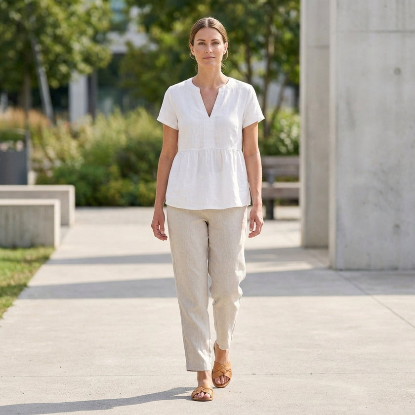 FJØRNA women's V-neck peplum blouse with pintuck details and curved hem, styled in a casual outfit.