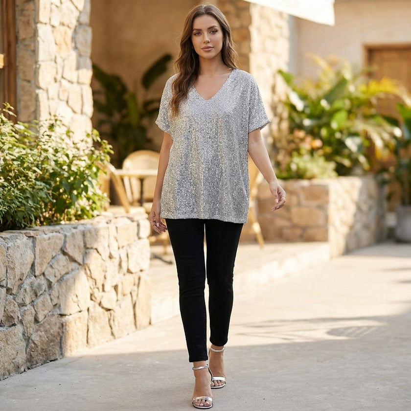 Women’s sequined V-neck top by FJØRNA, draped short sleeves, perfect for evening wear, styled in a fashionable lifestyle setting.