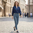 FJØRNA summer women's blouse with V-neck, puff sleeves, and pleated design worn by a model outdoors.