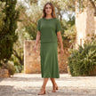 FJØRNA flowing midi dress and cropped open-knit mesh top set worn in a stylish lifestyle setting.