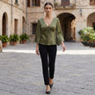 FJØRNA women's summer blouse with V-neck, satin fabric, high waist, styled with casual accessories in a relaxed outdoor setting.