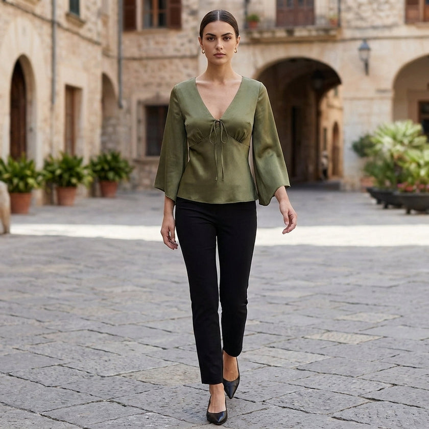 FJØRNA women's summer blouse with V-neck, satin fabric, high waist, styled with casual accessories in a relaxed outdoor setting.