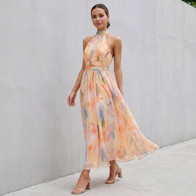 FJØRNA pleated belted A-line halter neck maxi dress worn by a woman outdoors, showcasing its flowy fabric and stylish design.