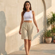 Women’s linen summer shorts with high waist and pockets, lightweight and stylish, by FJØRNA, shown in a casual outdoor setting.