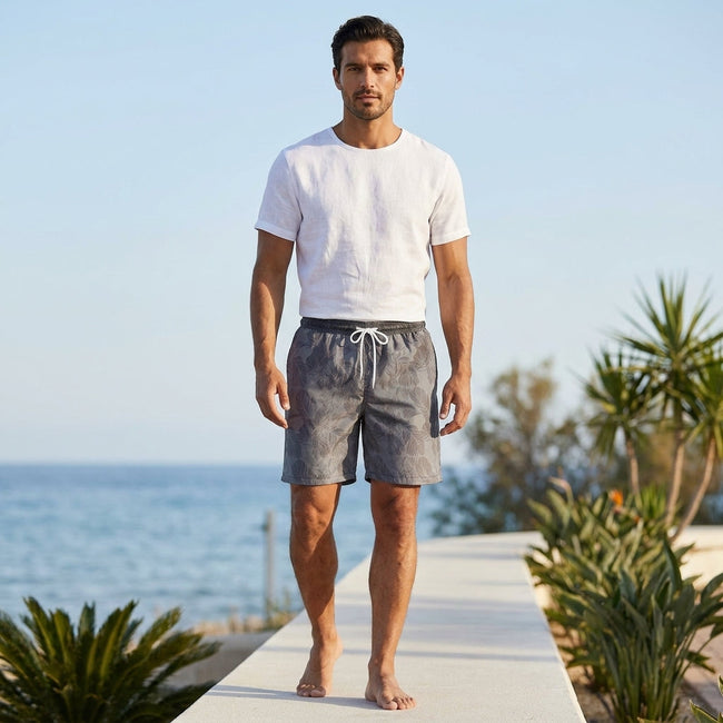 Men's knee-length shorts by FJØRNA with a relaxed fit and gradient botanical design, shown in a casual lifestyle setting.