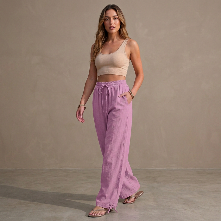Women’s linen summer trousers by FJØRNA with pockets and drawstring, styled casually in a bright outdoor setting.