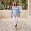 FJØRNA elegant mini dress for women with a V-neckline and ruffle details, styled in a casual outdoor setting.