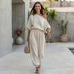 FJØRNA draped one-shoulder top with voluminous lantern pants set, perfect for resort chic, styled in a relaxed lifestyle setting.