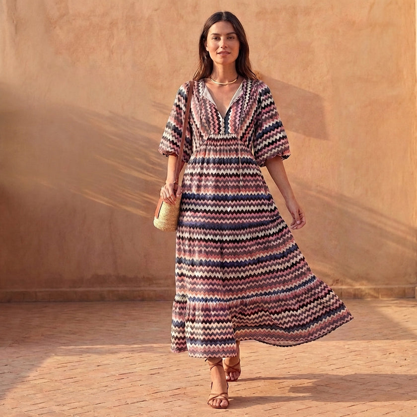 FJØRNA elegant flowy V-neck midi dress with puff sleeves and tiered skirt, styled in a casual outdoor setting.