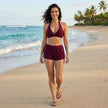 FJØRNA women's summer bikini with halter neck and ruched design, shown on a model in a beach setting.