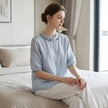 FJØRNA women's summer linen blouse with ruffle details, styled as a casual top in a relaxed lifestyle setting.