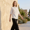 FJØRNA summer women's denim blouse with ruffle details, styled casually with rolled-up sleeves and a relaxed fit.