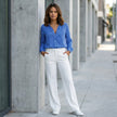 FJØRNA women's summer blouse with geometric pattern, V-neck, and long sleeves, styled casually in a lifestyle setting.