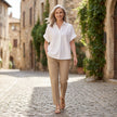FJØRNA women's summer blouse with short sleeves and denim fabric, styled with wide-leg pants in a casual outdoor setting.