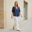 FJØRNA summer women's blouse with V-neck and puff sleeves, styled casually with a relaxed fit and lightweight fabric.
