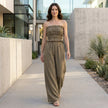 FJØRNA smocked strapless top and wide-leg pants resort set worn by a model in a stylish outdoor setting.