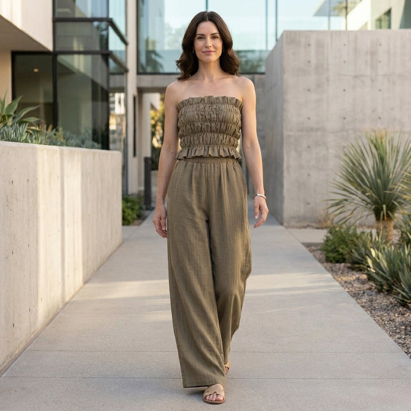 FJØRNA smocked strapless top and wide-leg pants resort set worn by a model in a stylish outdoor setting.
