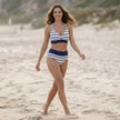 FJØRNA women's summer bikini with halter neck and high waist, shown on a model in a beach setting. Bright, stylish swimwear.