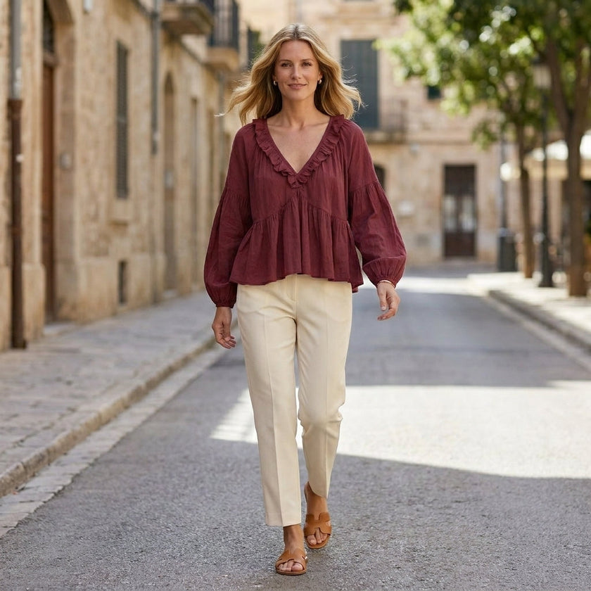 FJØRNA women's summer blouse with V-neck, long sleeves, denim fabric, and ruffle details, styled in a casual outdoor setting.