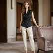 FJØRNA women's sleeveless satin summer blouse with V-neck, shown styled with casual accessories in a lifestyle setting.